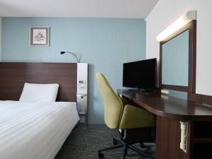 a bedroom with a desk with a bed and a computer at Comfort Hotel Sendai West in Sendai