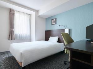 a hotel room with a large bed and a desk at Comfort Hotel Sendai West in Sendai