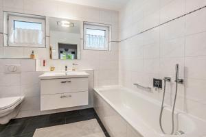 a white bathroom with a tub and a sink and a toilet at Bernhards in Buch +16 photos