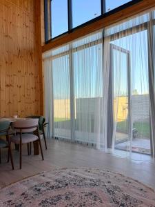 a living room with a table and a large window at Barnhouse Allan in Koshkolʼ
