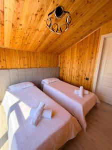 two beds in a room with a wooden ceiling at Barnhouse Allan in Koshkolʼ
