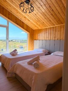 two beds in a room with a large window at Barnhouse Allan in Koshkolʼ