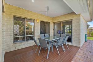 a patio with a table and chairs on a deck at The Seahaven - Modern 5 Bedroom Family Home Close to Beach in Pialba