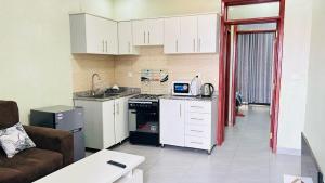 a kitchen with white cabinets and a living room at Relaxing Lodge in Kigali