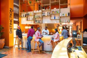 a group of people standing around a bar in a restaurant at Illovo Hotel in Johannesburg