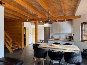 a kitchen with wooden ceilings and a large island with black chairs at Przystanek Beskidy in Brenna