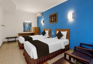 a hotel room with two beds and a blue wall at Townhouse Oak Hotel Lestari in Berpodak