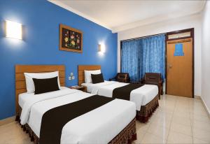 two beds in a hotel room with blue walls at Townhouse Oak Hotel Lestari in Berpodak