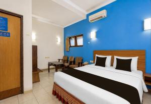 a bedroom with a large bed and a blue wall at Townhouse Oak Hotel Lestari in Berpodak