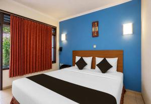 a bedroom with a large bed with blue walls at Townhouse Oak Hotel Lestari in Berpodak