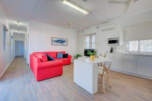 a living room with a red couch and a kitchen at Ruby in Exmouth