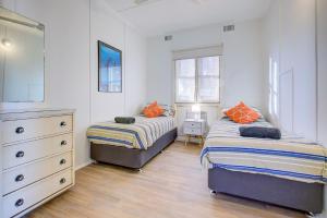 a bedroom with two beds and a dresser and window at Ruby in Exmouth