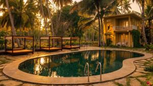 a swimming pool in front of a house with palm trees at Samadhi by the Venus Project in Ranna