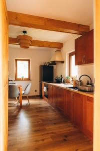 a kitchen with wooden cabinets and a table and a counter at Między łąką a lasem in Żdżar