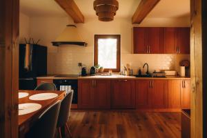 a kitchen with wooden cabinets and a table and a sink at Między łąką a lasem in Żdżar
