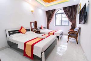 a hotel room with two beds and a desk at Khách sạn Tuyết Minh in Xã Thang Tam