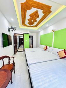 a room with two beds and a table and a green wall at Khách sạn Tuyết Minh in Xã Thang Tam
