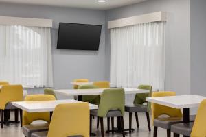 a room with tables and chairs with a tv on the wall at Baymont by Wyndham La Grange KY Southeast in La Grange
