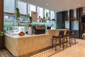a restaurant with a bar with stools and a counter at Ramada Encore Istanbul Bayrampasa in Istanbul