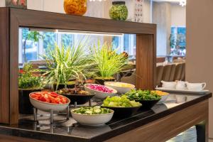 a buffet line with bowls of vegetables and plants at Ramada Encore Istanbul Bayrampasa in Istanbul +30 photos