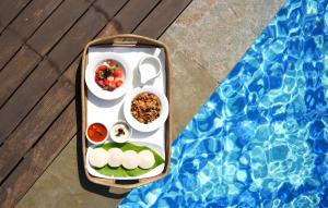 a bento box with food in it next to a pool at Miros, Goa in Old Goa