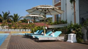 a row of lounge chairs with umbrellas next to a pool at Miros, Goa in Old Goa +68 photos