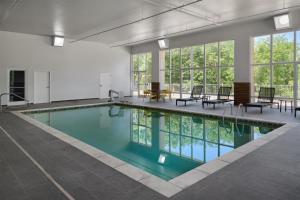 a swimming pool with chairs and a table and windows at Hampton Inn Lawrence in Lawrence