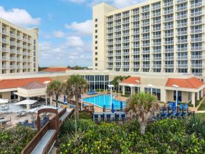 a view of the resort with a pool and palm trees at Hilton Melbourne Beach Oceanfront in Melbourne