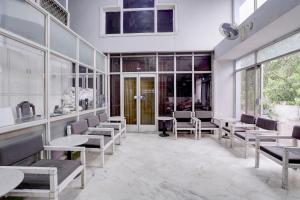 a waiting room with chairs and tables and windows at Hotel O Bhavnagar Bus Terminal Formerly Jubliee in Bhavnagar