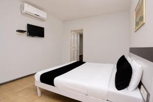 a white bedroom with a white bed with black and white pillows at Hotel O Bhavnagar Bus Terminal Formerly Jubliee in Bhavnagar