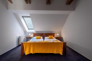 a bedroom with a bed with a yellow blanket on it at Serenity Residence Hotel & Wellness in Liptovský Trnovec