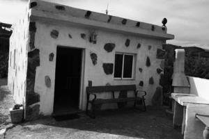 un pequeño edificio con un banco delante en Casa Rural Anzo, en Gáldar