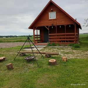 a wooden cabin with a pile of logs in front of it at domek letniskowy Agroturystyka Sajkiewicz in Chmielnik