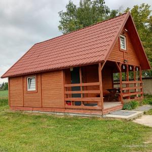 a large wooden cabin with a red roof at domek letniskowy Agroturystyka Sajkiewicz in Chmielnik