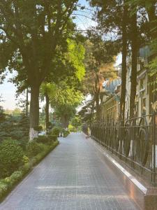a cobblestone street with trees and a fence at KHAN Hotel in Kokand