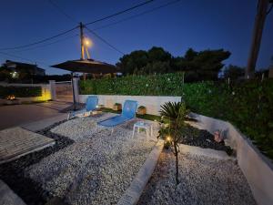 a patio with chairs and an umbrella at night at Greek Memories in Artemida