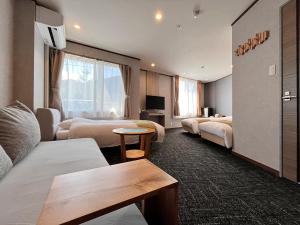 a hotel room with beds and a couch and a table at Hotel Cerulean Alpine in Otari +65 photos