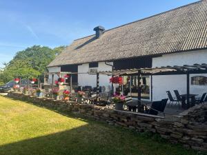a building with a stone wall and chairs and flowers at Drottning Ödas Boende in Degerhamn