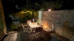 a table and chairs sitting next to a stone wall at night at Verde Salvia House in Corniglio