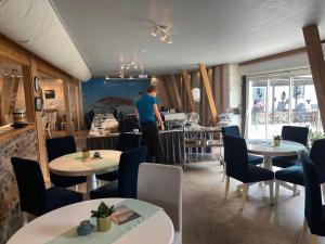 a man standing in a restaurant with tables and chairs at Drottning Ödas Boende in Degerhamn