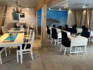 a dining room with white tables and black chairs at Drottning Ödas Boende in Degerhamn +26 photos