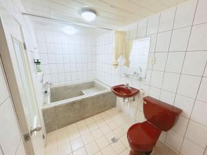 a bathroom with a red toilet and a bath tub at 心園生活旅店 Xin Yuan Hotel in Hsinchu City +29 photos