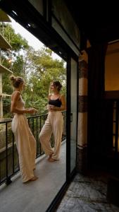 a woman standing on a balcony in front of a mirror at A Lounge Hostel in Ella