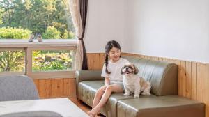 a little girl sitting on a couch with a dog at suncheon romance pension in Suncheon