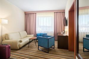 a hotel room with a couch and a television at Hotel Victor Pruszków DeSilva in Pruszków