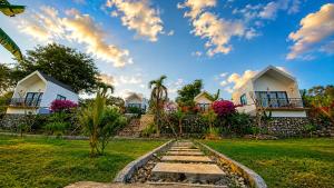 a row of cottages in a garden with a cloudy sky at Penida Cabins in Nusa Penida