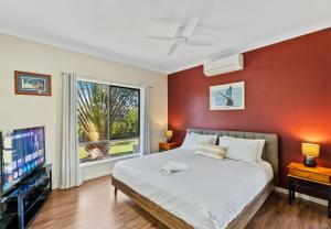 a bedroom with a bed and a tv at The Seahaven - Modern 5 Bedroom Family Home Close to Beach in Pialba