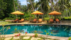 a swimming pool with chairs and umbrellas at Samadhi by the Venus Project in Ranna +56 photos