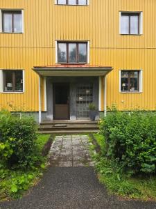 a yellow building with a door and a porch at Small cozy basement apartment in Sundsvall