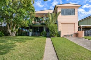a house with a tree and a driveway at Waterfront Delight on Cater in Sussex Inlet